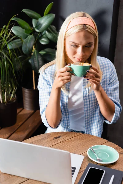 Blonde Freiberuflerin Trinkt Kaffee Der Nähe Von Laptop Und Smartphone — Stockfoto