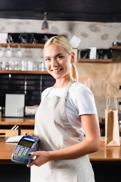 Önlüklü Neşeli Sarışın Barista Kameraya Bakarken Ödeme Terminalini Tutuyor — Stok fotoğraf