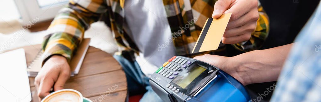 cropped view of man with credit card near waiter holding payment terminal, banner