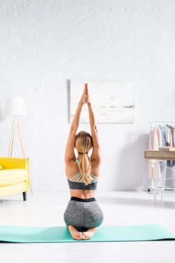 Sarışın kadının yoga egzersizi sırasında spor minderinde oturuşu. 