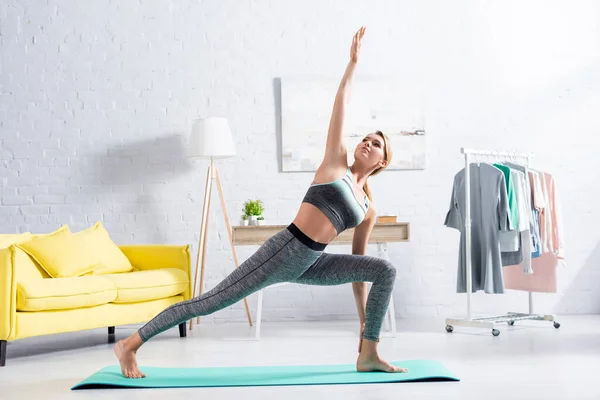金发女运动员站在健身垫上练瑜伽 — 图库照片