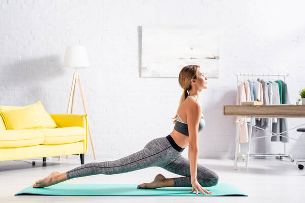 Young sportswoman looking away while practicing yoga on fitness mat at home