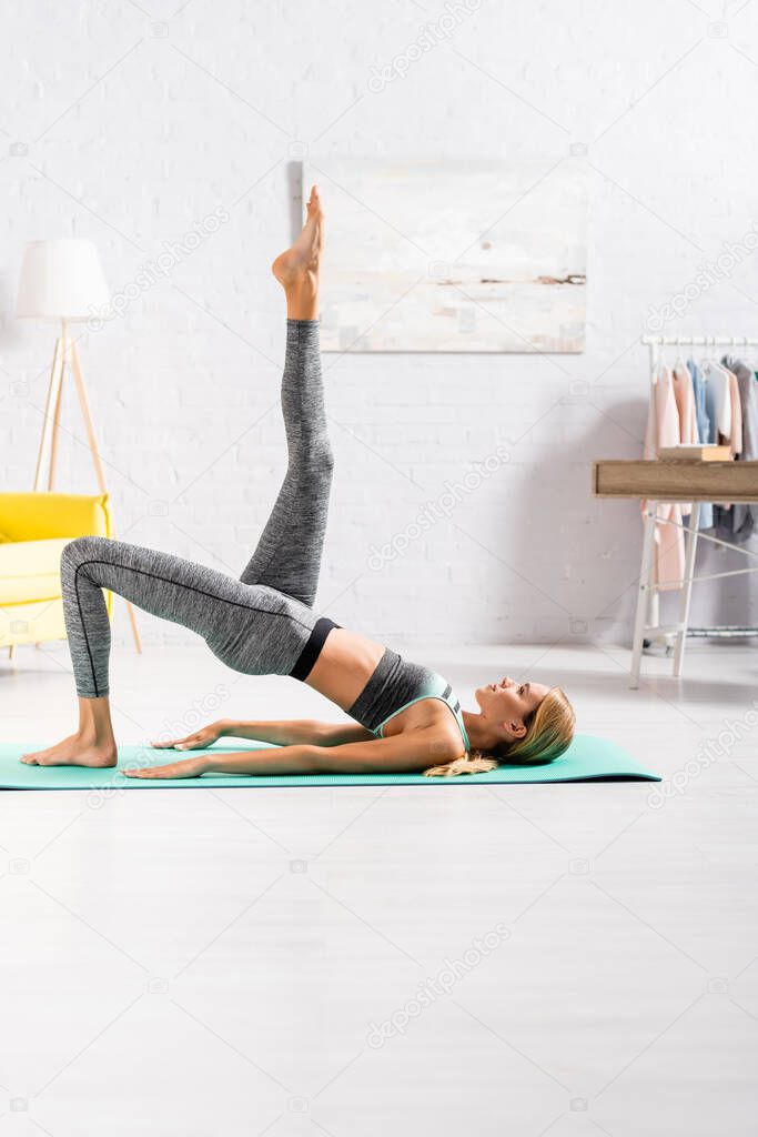 Side view of woman with raised leg practicing yoga at home 