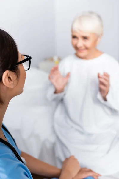 Νεαρή Νοσοκόμα Ακούει Χαρούμενα Ηλικιωμένη Γυναίκα Gesturing Ενώ Μιλάμε Για — Φωτογραφία Αρχείου