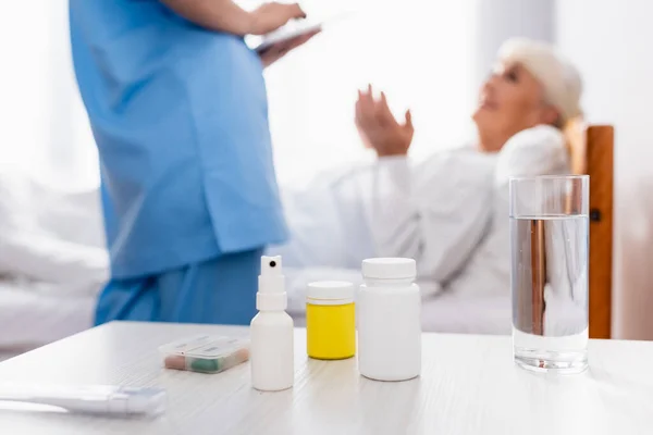 Tabela Com Comprimidos Recipientes Spray Garganta Vidro Água Perto Enfermeira — Fotografia de Stock