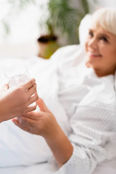 Sjuksköterska Ger Ett Glas Vatten Till Leende Äldre Kvinna Sjukhus — Stockfoto