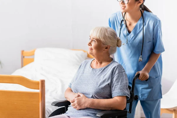 Young Nurse Smiling Aged Woman Sitting Wheelchair Looking Away — Stock Photo, Image