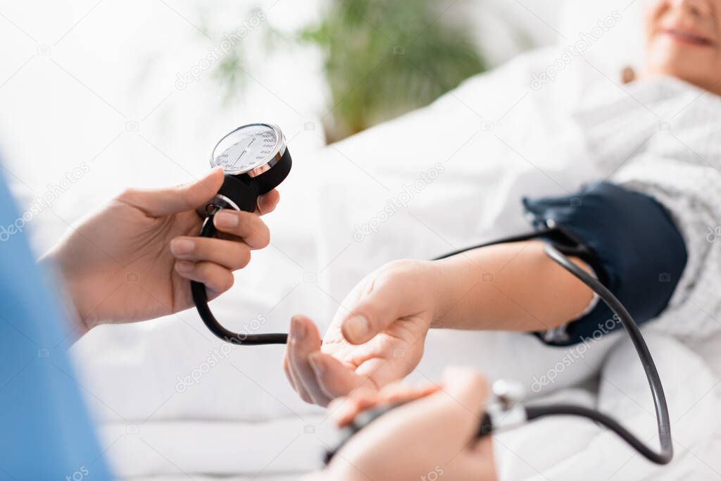 selective focus of nurse measuring blood pressure of aged woman