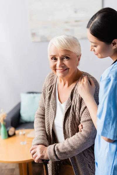 Glad Äldre Kvinna Med Promenadkäpp Ler Mot Kameran Nära Ung — Stockfoto