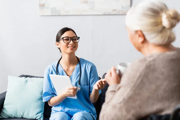 Cheerful Asian Woman Digital Tablet Talking Senior Woman Holding Cup — Stock Photo, Image