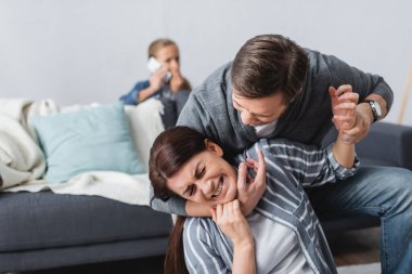 Öfkeli adam karısını boğarken çocuk da arka planda akıllı telefondan konuşuyor. 