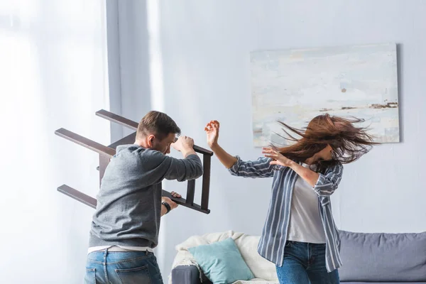 Abuso Hombre Sosteniendo Silla Cerca Gritando Esposa Casa —  Fotos de Stock