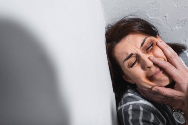 Küfürbaz koca, duvarları morarmış, gücenmiş karısının yüzüne dokunuyor. 
