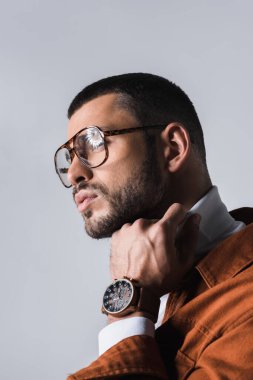 Gözlüklü bir adamın portresi. Gri boğazlı kazağı düzeltiyor. 