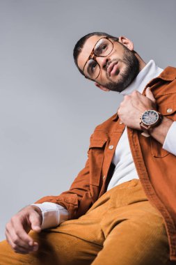 Gri üzerine izole bir şekilde bakan şık bir adamın düşük açılı görüntüsü. 