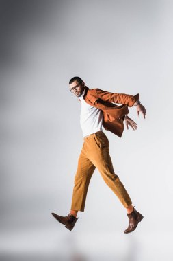 Moda adamı gri arka planda kameraya bakıyor. 