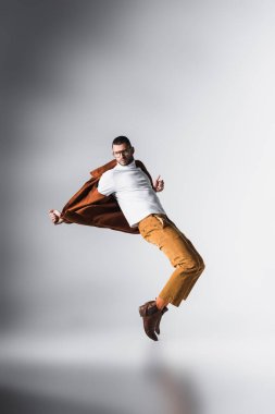 Terracotta ceketli genç adam ve gri arka planda poz veren beyaz balıkçı yaka. 