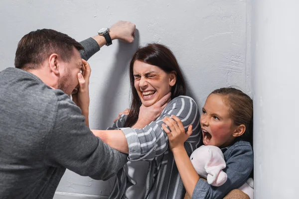 Abusador Sufocando Esposa Com Hematomas Perto Criança Gritando Com Brinquedo — Fotografia de Stock