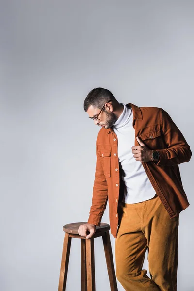 Homem Elegante Ajustando Jaqueta Perto Cadeira Madeira Isolada Cinza — Fotografia de Stock