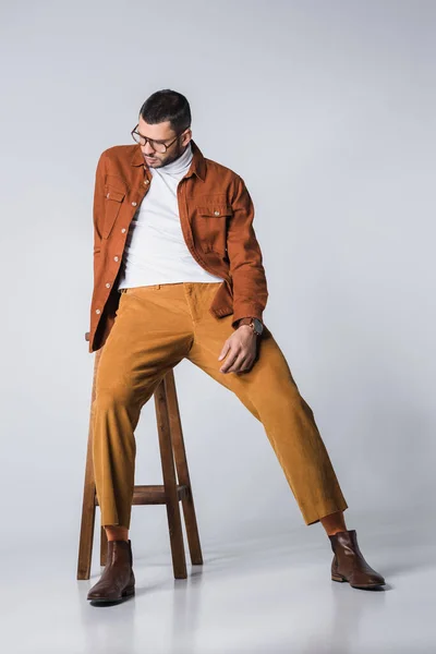 Junger Stylischer Mann Mit Brille Sitzt Auf Stuhl Vor Grauem — Stockfoto