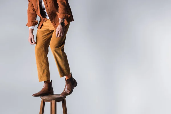 穿着棕色鞋子的时髦男人站在灰色背景的木制椅子上的剪影 — 图库照片