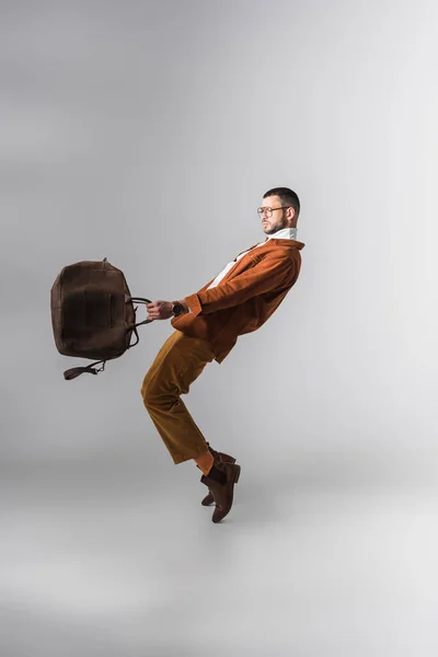 Elegante Hombre Sosteniendo Bolsa Marrón Mientras Posa Sobre Fondo Gris — Foto de Stock