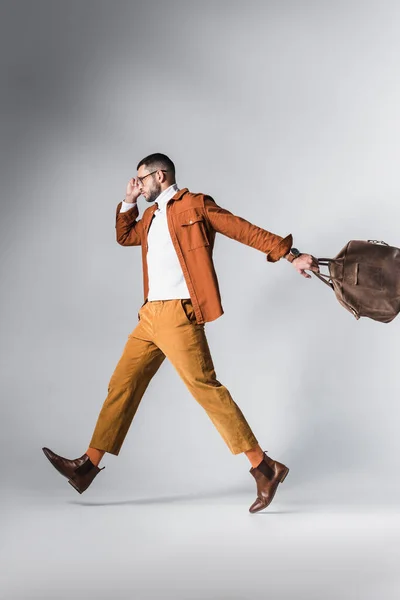 Homem Moda Segurando Saco Marrom Enquanto Caminha Sobre Fundo Cinza — Fotografia de Stock