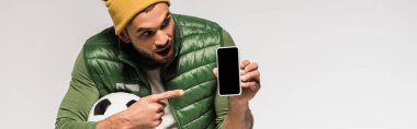 Gri pankartta izole edilmiş akıllı telefonu işaret eden heyecanlı sporcu. 