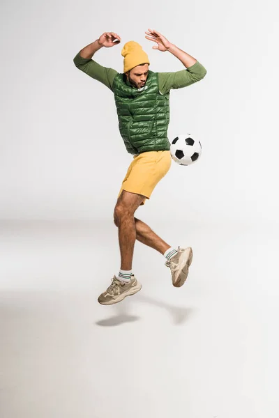 Esportista Animado Pulando Enquanto Joga Futebol Fundo Cinza — Fotografia de Stock