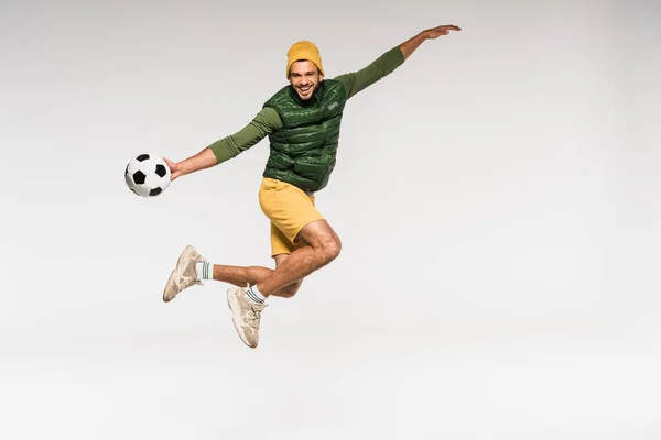 Fröhlicher Sportler Freizeitkleidung Springt Und Hält Fußball Isoliert Auf Grau — Stockfoto