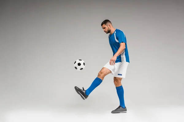 スポーツウェアの男は灰色の背景でサッカーをプレイ — ストック写真