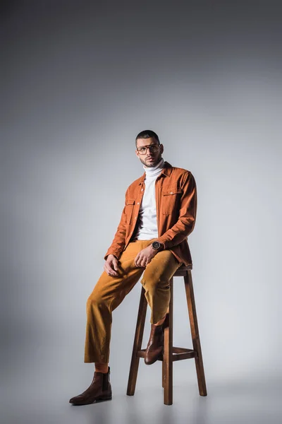 Elegante Hombre Mirando Hacia Otro Lado Silla Sobre Fondo Gris — Foto de Stock