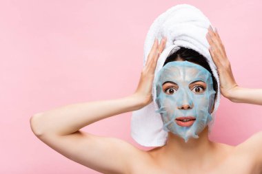 Şok olmuş, yüzü maske kaplı güzel bir kadın pembe bir yüzle izole edilmiş.