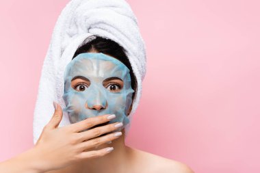 Şok olmuş, yüzü maske kaplı güzel bir kadın pembe bir yüzle izole edilmiş.