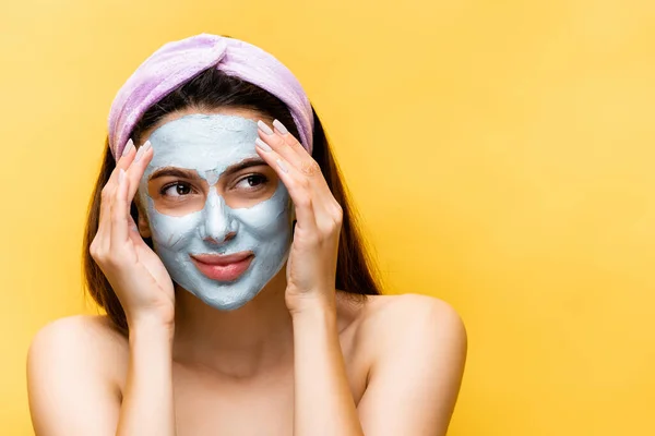 beautiful woman with clay mask on face isolated on yellow