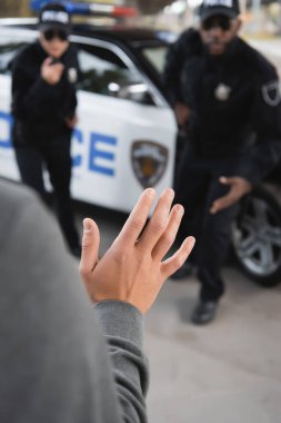 Saldırganın arka planda bulanık çok kültürlü polis memurlarıyla el ele tutuşurken görüntüsünü kapatın.