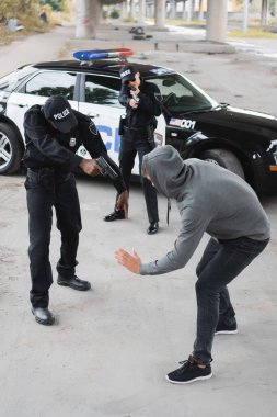 Arka plandaki bulanık alanda teslim olmuş suçluları hedef alan çok kültürlü polis memurlarının yüksek açılı görüntüsü