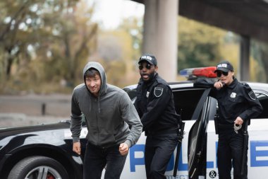 Şok olmuş çok kültürlü polis memurlarından kaçan kapüşonlu bir suçlu şehir sokaklarında bulanık bir geçmişe sahip.