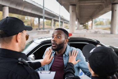 Polis memurlarının, arka planda bulanık arka planda devriye arabasının yakınındaki afro-amerikan kurbanlarını sakinleştirdiğini gördüm.