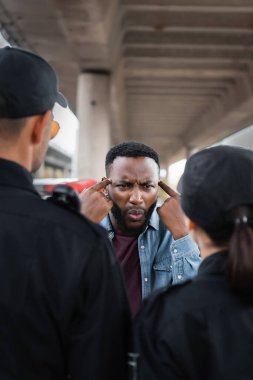 Kızgın Afro-Amerikalı kurban dışarıda ön planda polis memurlarıyla tartışırken çılgınca bir hareket yaptığını gösteriyor.