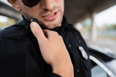 Güneş gözlüklü polis dışarıda telsiz kullanıyor. 