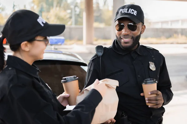 Gelukkig Politievrouw Met Papier Beker Geven Pakket Naar Afrikaans Amerikaanse — Stockfoto