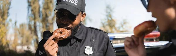 Afro Amerikai Rendőrtiszt Fánkot Eszik Homályos Kollégával Szabadban Transzparens — Stock Fotó