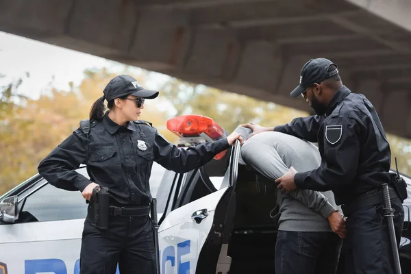 Multicultural Police Officers Arresting Hooded Offender Colleague Patrol Car Urban — Stock Photo, Image