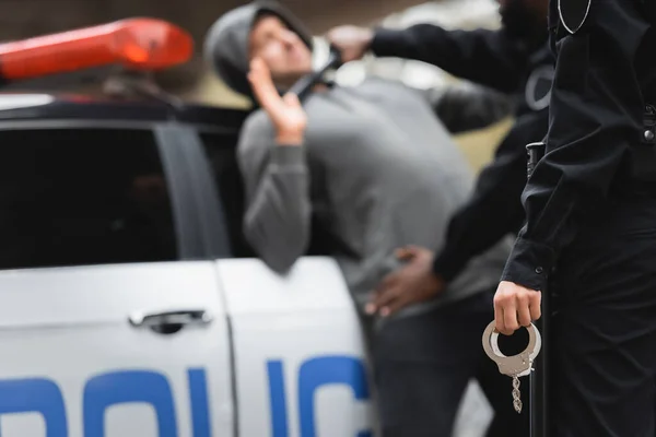 Polizistin Mit Handschellen Mit Verschwommenem Multikulturellen Polizisten Und Täter Hintergrund — Stockfoto