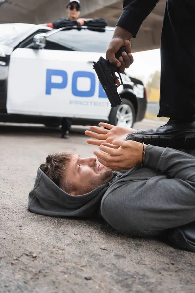 Africký Americký Policista Míří Pistolí Vyděšený Pachatel Ležící Ulici Rozmazané — Stock fotografie