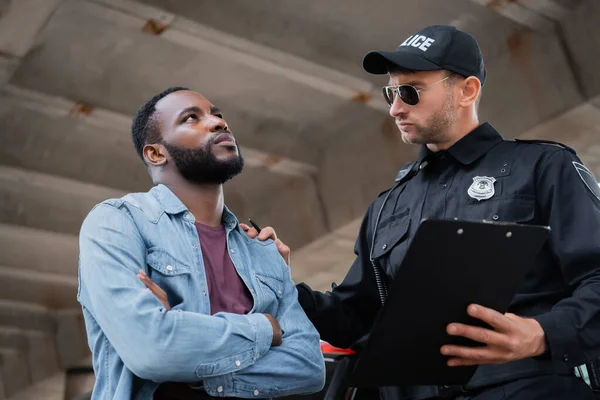 Police Officer Calming African American Victim While Holding Clipboard Blurred — Stock Photo, Image