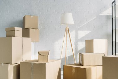 Modern apartmandaki lambanın yanında bir yığın karton kutu. 
