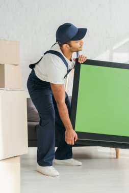 Dairesinde yeşil ekran olan plazma televizyon taşıyan Hintli bir nakliyeci. 