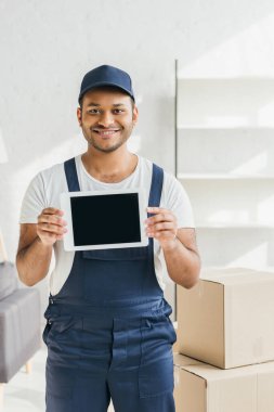 Gülümseyen Hintli üniformalı işçi dairede boş ekranlı dijital tablet tutuyor. 